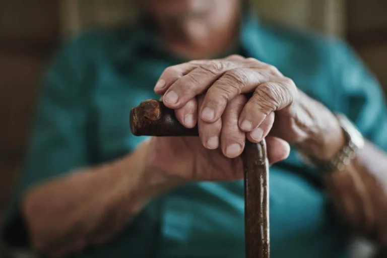 Nursing home resident holding his cane in front of him.