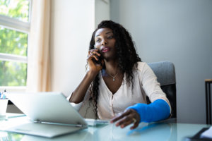 Woman with broken arm on the phone making a personal injury claim