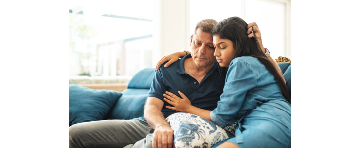 A father and daughter sitting on the couch, grieving