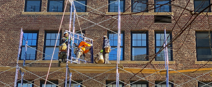 Construction workers standing on scaffolding on the side of a building