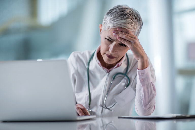 Worried doctor having some problems while working on laptop in the office.