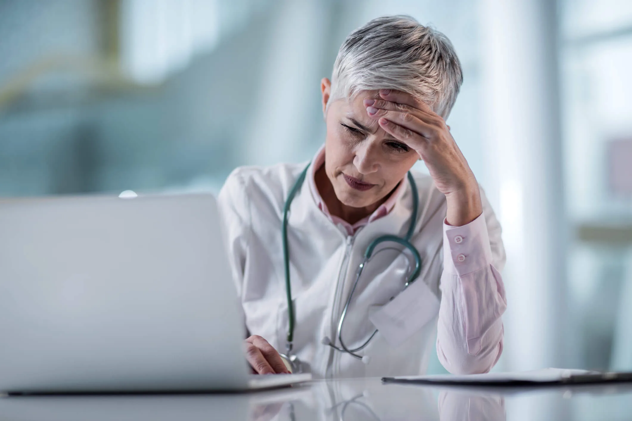 Worried doctor having some problems while working on laptop in the office.